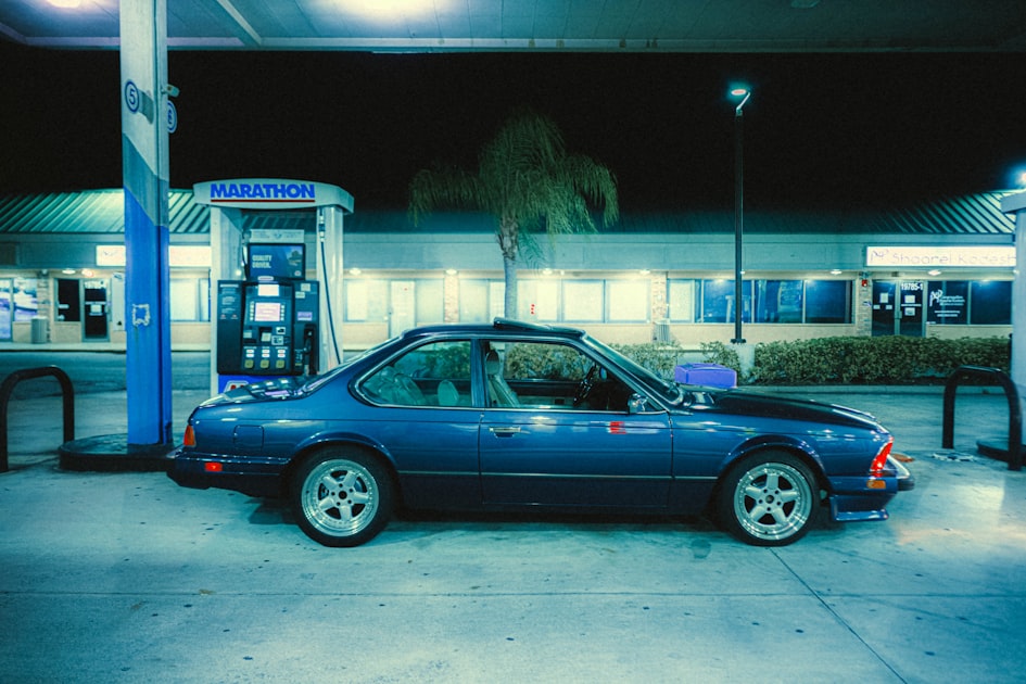 a blue car parked in front of a gas station
