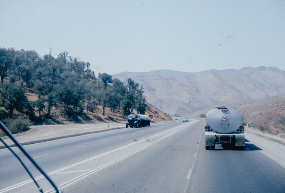 a tanker truck driving down a highway next to a forest