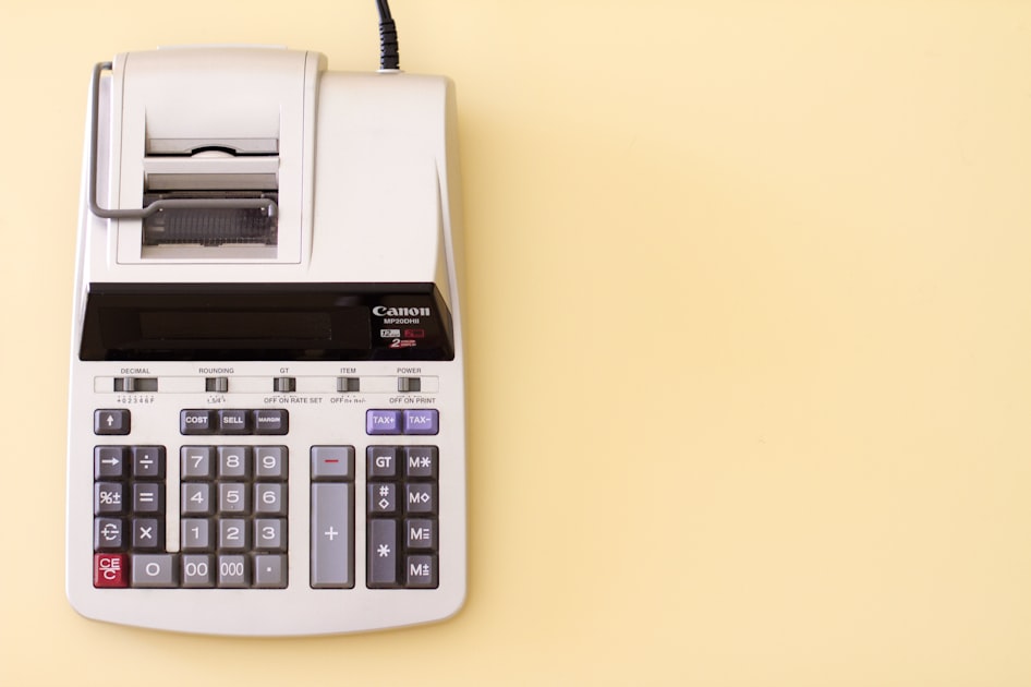 A grey printing calculator on a light yellow background