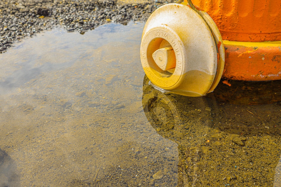 a yellow and orange fire hydrant sitting in a puddle of water